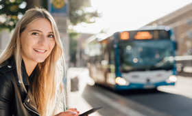 junge Frau an einer Bushaltestelle in Heilbronn, ein Stadtbus nähert sich